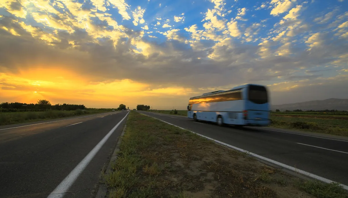 Ônibus rodoviário em estrada reta ao amanhecer
